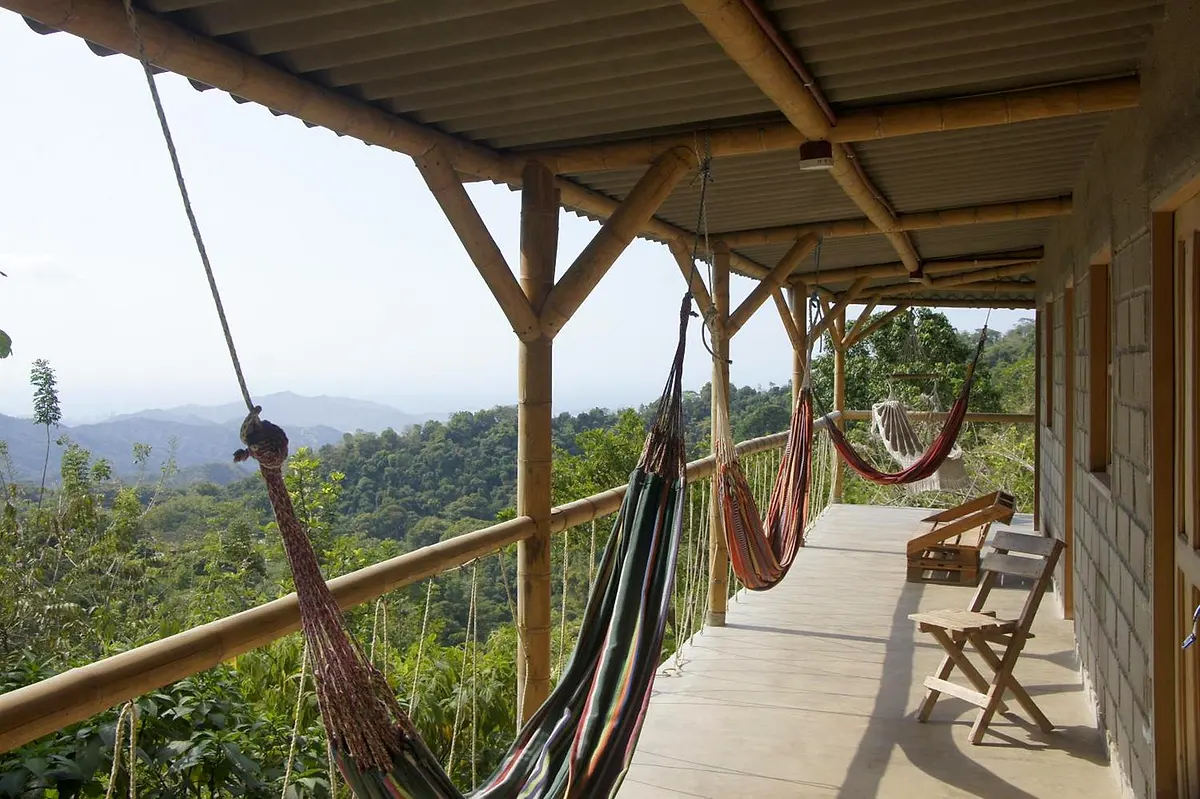 A porch with hammocks looking out to layered green mountains